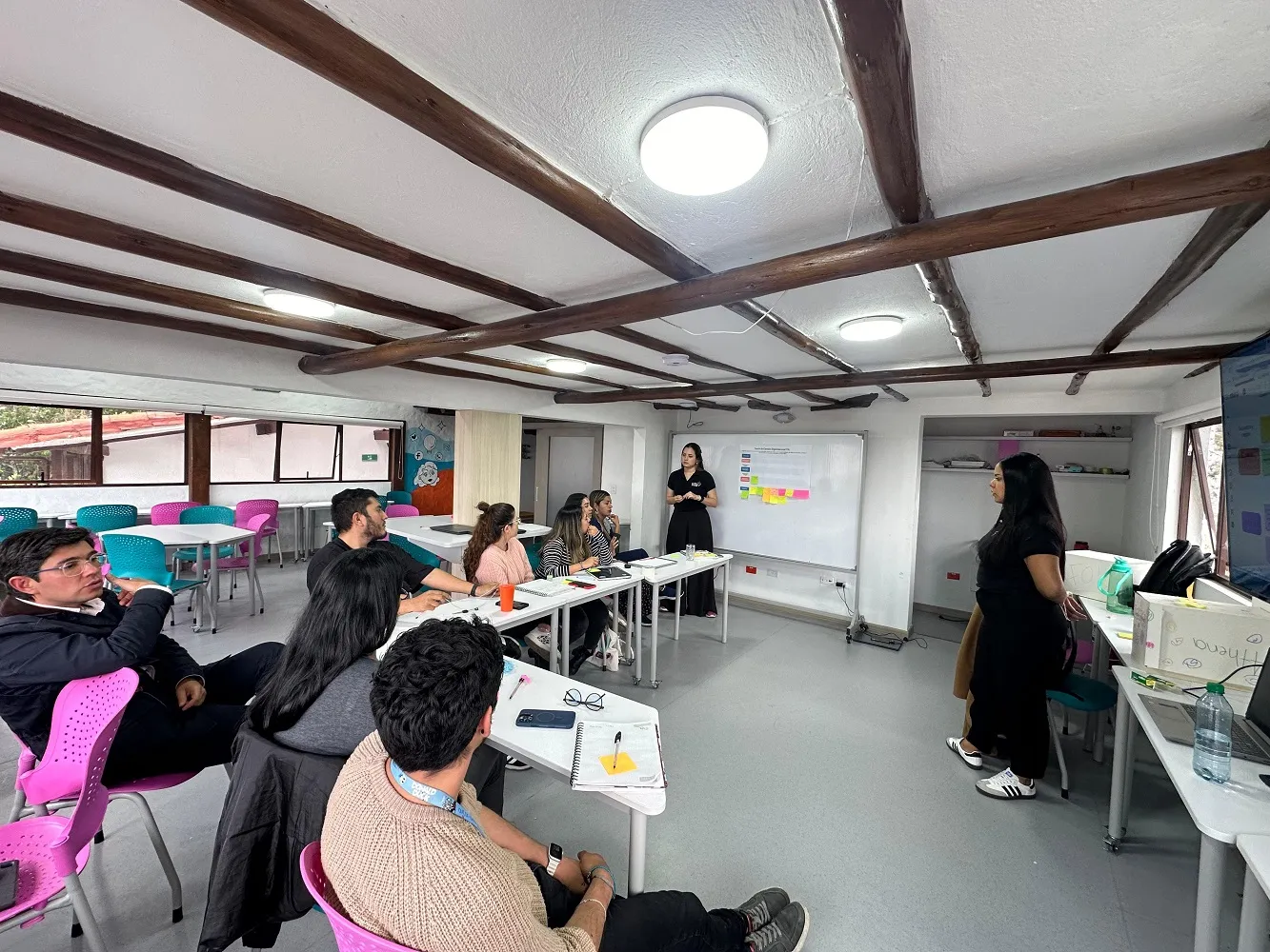 Taller en un salón amplio con participantes trabajando en mesas y material de trabajo sobre las paredes.